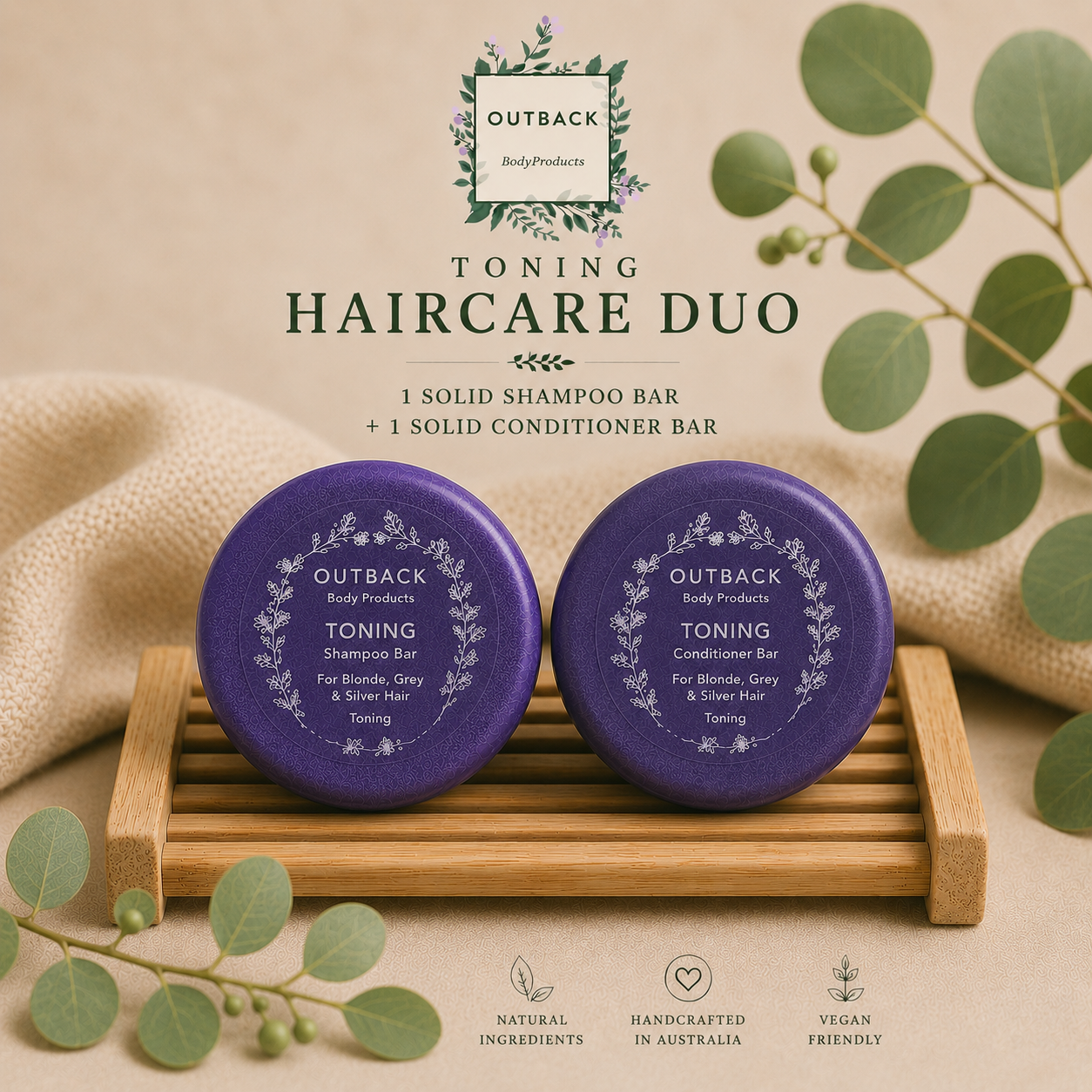 Two purple shampoo and conditioner bars on a wooden stand with green leaves and Outback Body Products branding.