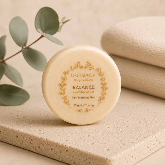 Outback Body Products Balance Conditioner Bar on a beige surface with eucalyptus leaves.