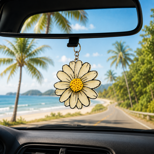 daisy car air freshener hanging from a car's rearview mirror with a scenic road and beach in the background.