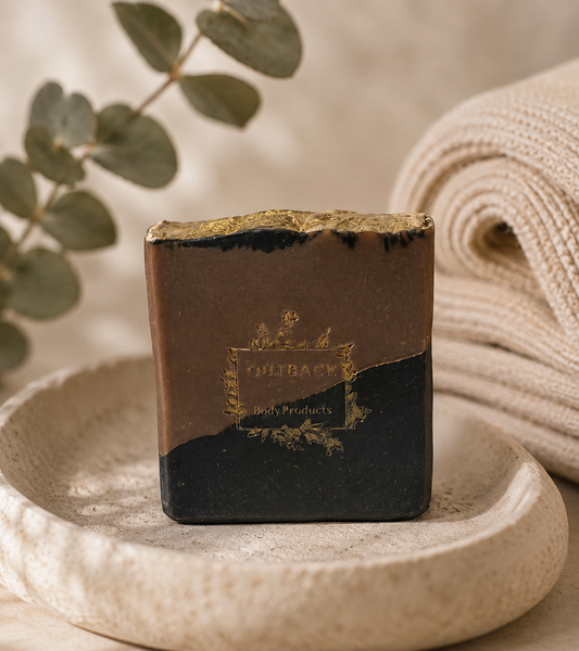 Bar of soap with a brand logo on a stone surface with eucalyptus leaves and a towel in the background