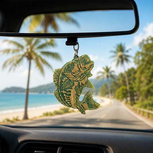 Fish-shaped car ornament hanging from a car's rearview mirror with a scenic road and beach in the background.
