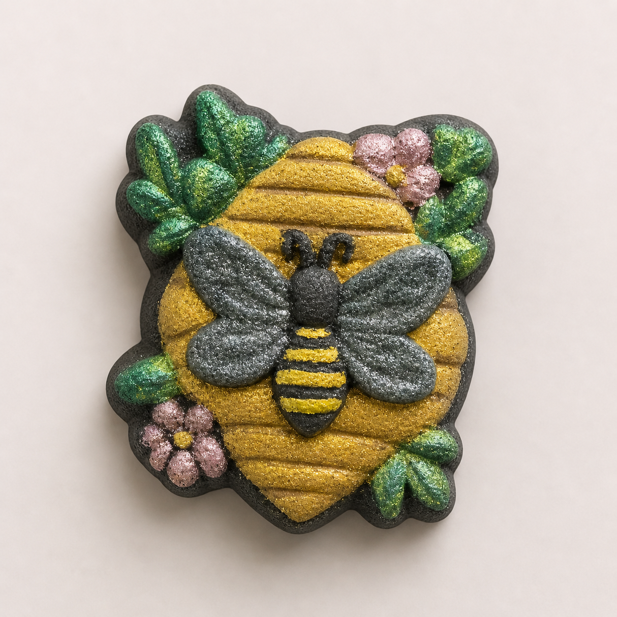 Decorative bath bomb with bee and honeycomb design on a beige background