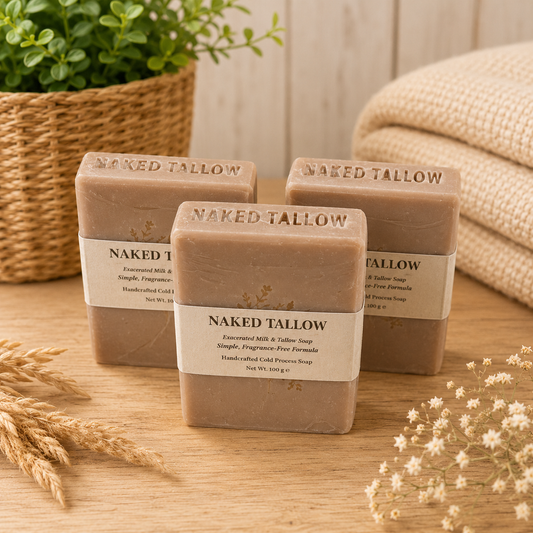 Three bars of Naked Tallow soap on a wooden surface with a plant and towel in the background.