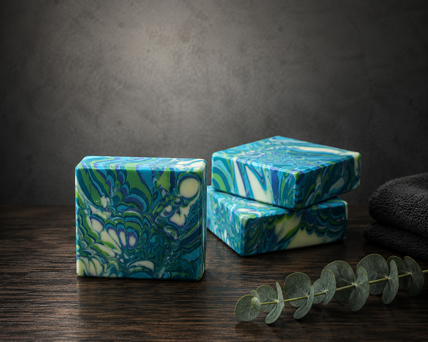 Marbled blue and green soap bars on a wooden surface with a dark background