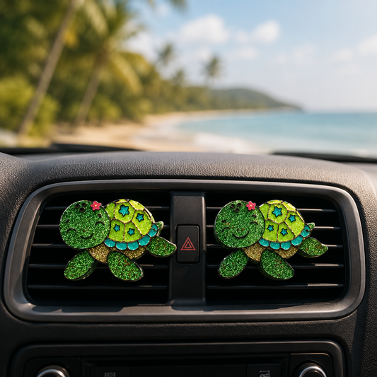 Two green turtle-shaped car air fresheners on a car vent with a beach background.