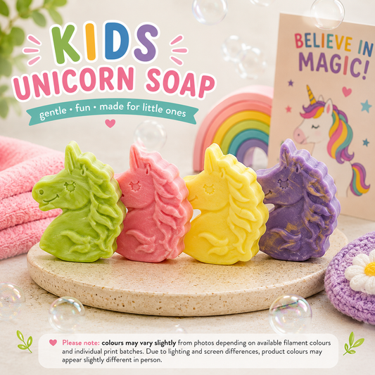 Four colorful unicorn-shaped soaps on a wooden board with a rainbow and unicorn-themed card in the background.
